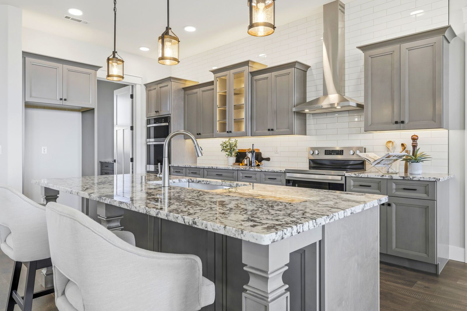 Finished gray shaker kitchen with white quartz island and chimney range hood