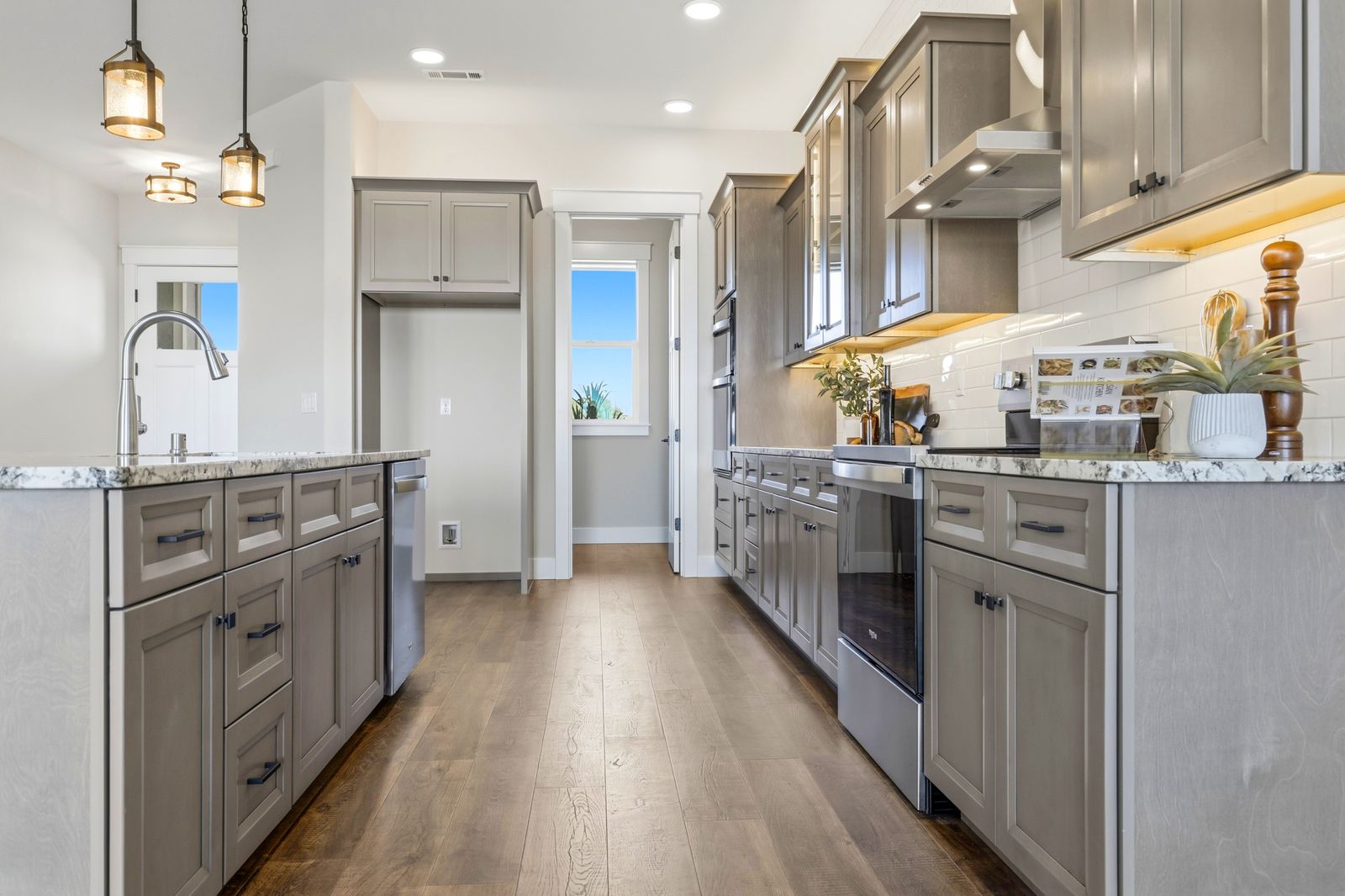 Galley view of the remodeled kitchen with wood floors and under-cabinet lighting